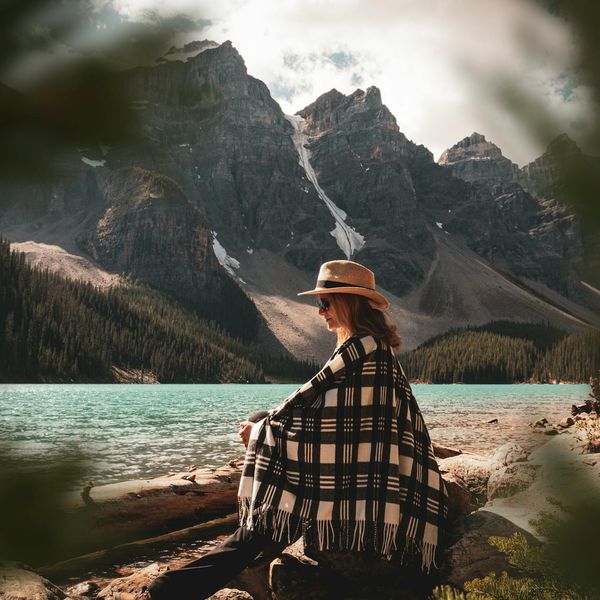 Person meditating peacefully outdoors near a calm lake.